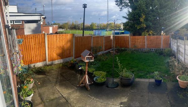 Back garden with new fence panels, paved patio, pots, bird table and lawn