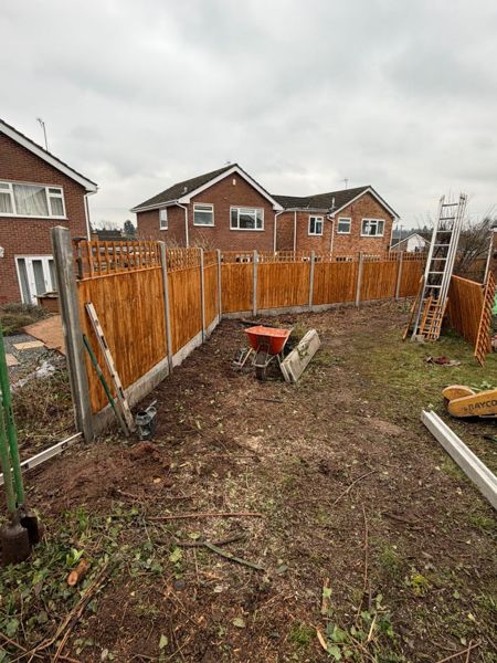 Close-board fence panels on concrete posts along the bare garden edge with a ladder and wheelbarrow