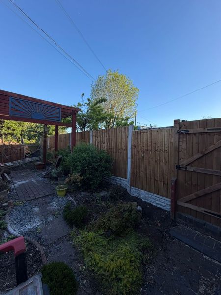 Fence panels on gravel boards leading to a braced timber gate beside brick paving and planted borders